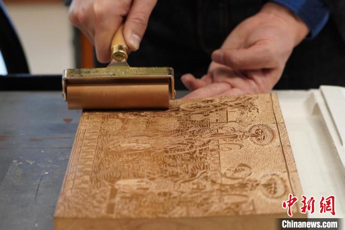 圖為徐晉林工作室工作人員正在給雕好壁畫的版面滾油墨?！【琶赖┰?　攝