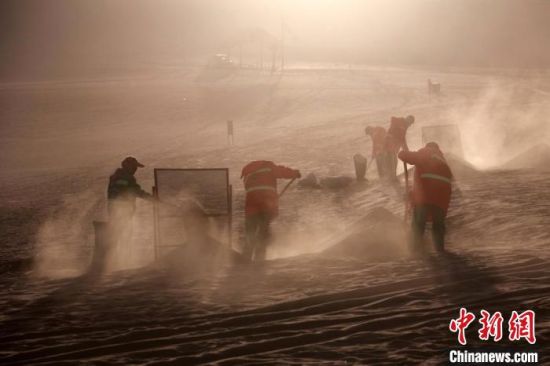 圖為敦煌市鳴沙山月牙泉景區(qū)“駱駝保姆”清理駱駝糞便?！垥粤?攝