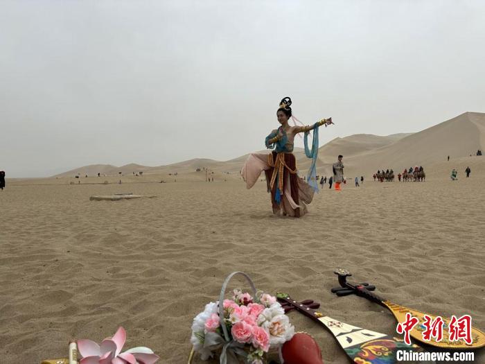 圖為2023年4月底，敦煌大漠“逐舞者”奧楠在鳴沙山月牙泉景區(qū)視頻直播敦煌舞?！●T志軍 攝