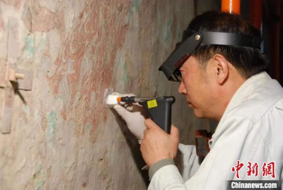 敦煌研究院研究員樊再軒進(jìn)行壁畫修復(fù)。(資料圖)張云文 攝